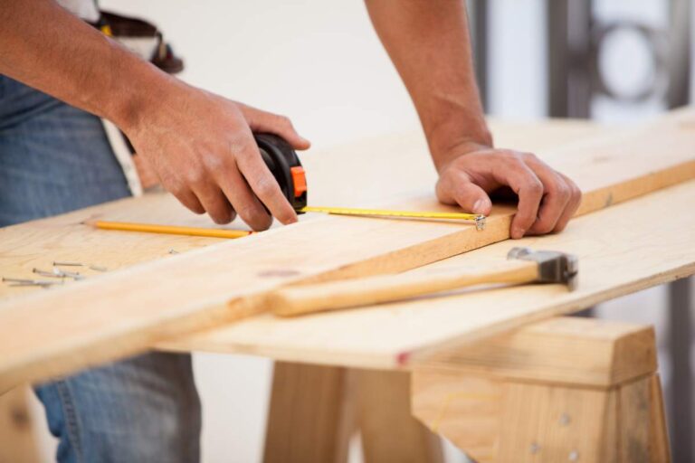 A homeowner and contractor reviewing blueprints at a kitchen island during a home remodeling consultation.